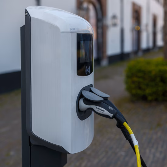 Borne de recharge pour véhicules électriques située sur un parking à proximité d'un bâtiment.