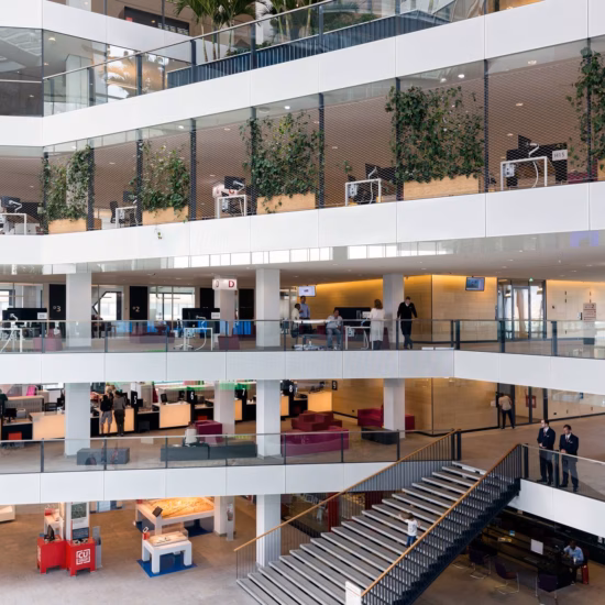 Interieur van een modern kantoorgebouw met open werkplekken, meerdere verdiepingen en geïntegreerd groen.