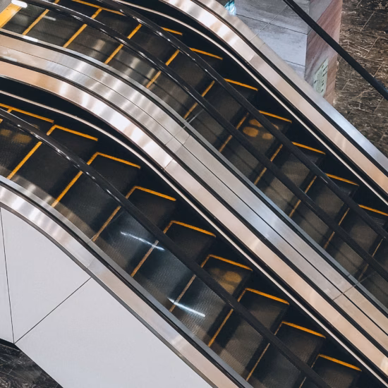 Plusieurs escaliers roulants se croisent dans un espace intérieur moderne à l'architecture épurée.