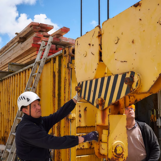 Ein Mitarbeiter führt Inspektions- oder Wartungsarbeiten an einer Hebeanlage auf einer Baustelle durch.