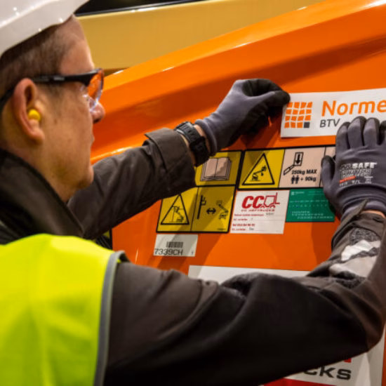 An employee inspects and applies safety markings to an industrial machine.