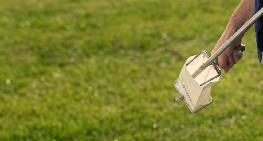 A sampling device collects a soil or grass sample from a grass field.