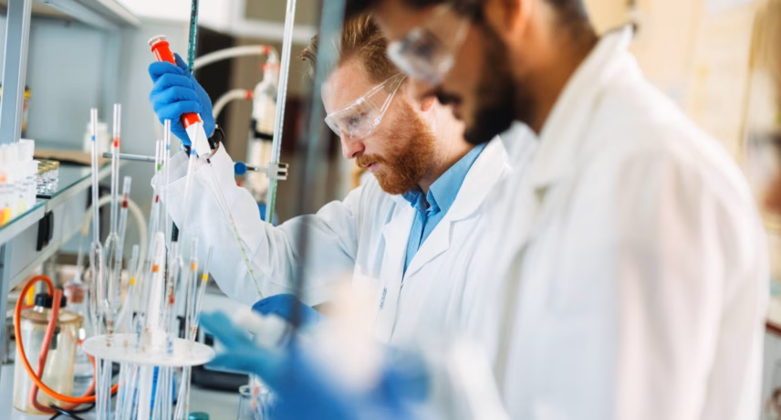 Laboratoriummedewerkers voeren chemische analyses uit met pipetten en laboratoriumapparatuur in een onderzoeksomgeving.