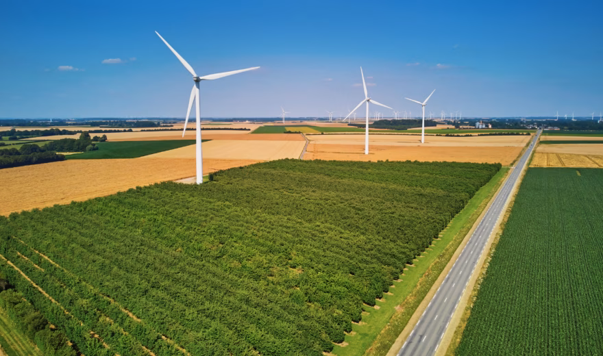 Wind turbines among farm fields in a rural landscape, as seen from the air.