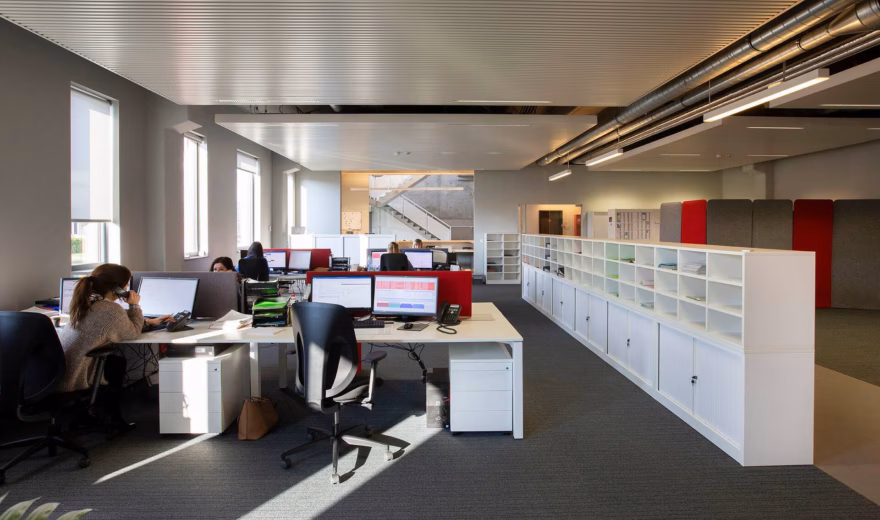 Moderne kantoorruimte met medewerkers aan werkplekken in een open kantooromgeving.