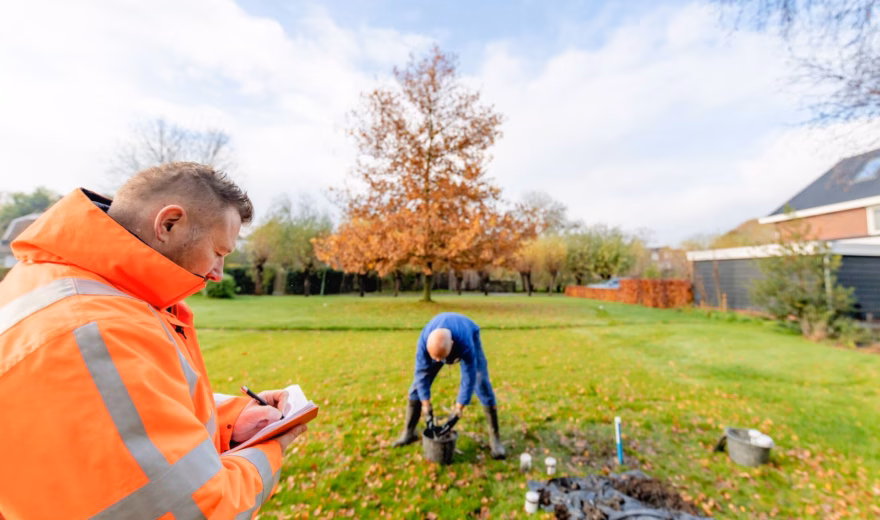 Soil survey in a garden, with two people using measuring equipment and tools to collect samples from a lawn.