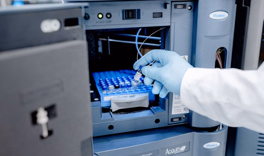 Un technicien de laboratoire place un échantillon dans un appareil d'analyse automatisé destiné aux analyses de laboratoire.