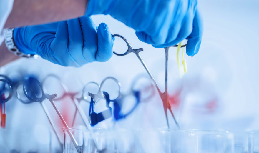Someone is picking up scissors from a medical tray in a clinical setting for medical purposes.