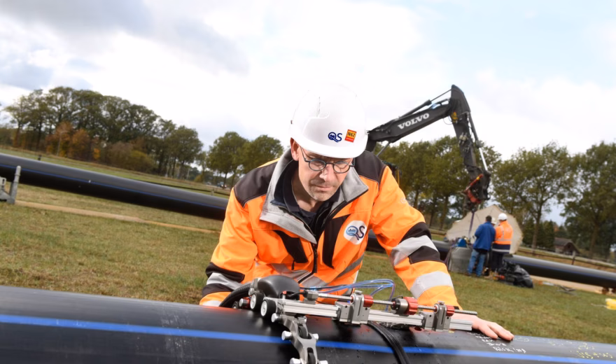 Technisch medewerker voert een lasinspectie uit op een pijpleiding met gespecialiseerde meetapparatuur.