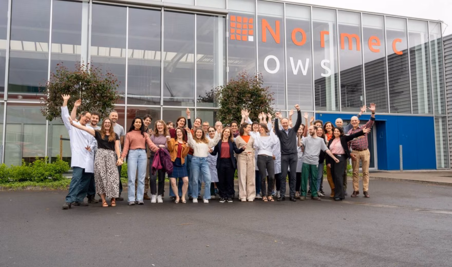 Groepsfoto van medewerkers voor een bedrijfspand van Normec OWS.