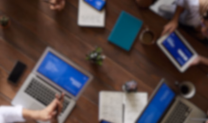 Top-Down-Ansicht von Fachkräften, die mit Laptops, Tablets, Notebooks und digitalen Präsentationen an einem Besprechungstisch zusammenarbeiten. Im Vordergrund stehen dabei strategische Planung, geschäftliche Zusammenarbeit, Projektmanagement, datengestützte Entscheidungsfindung und effektive Teamarbeit in einem modernen Unternehmensumfeld.