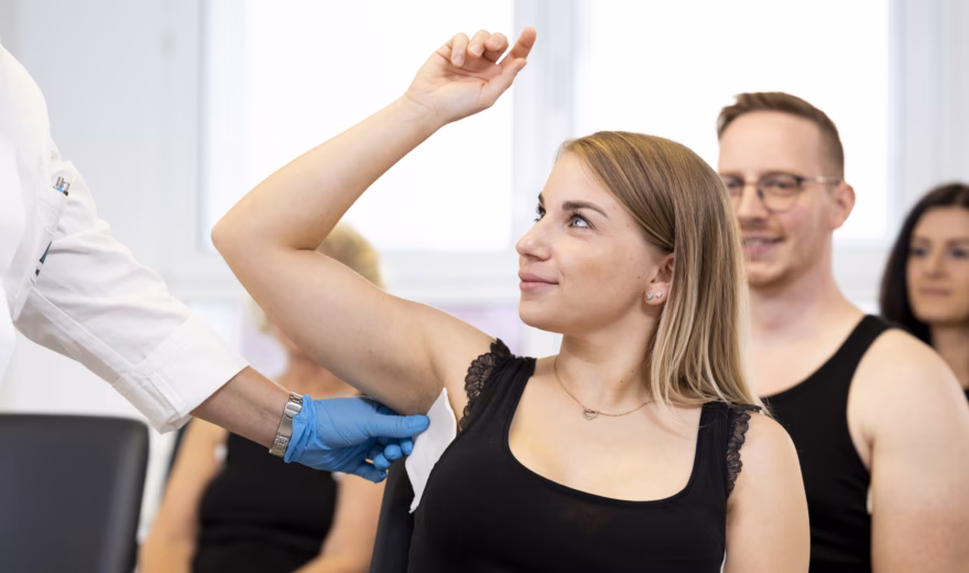 "Een patiënt die een medisch onderzoek ondergaat in een moderne kliniek, uitgevoerd door medisch personeel; op de achtergrond is medisch personeel te zien."