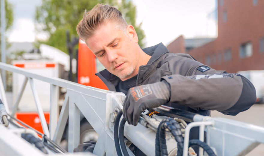 Technisch medewerker voert onderhouds- of inspectiewerkzaamheden uit aan een industriële constructie met kabels en technische componenten.