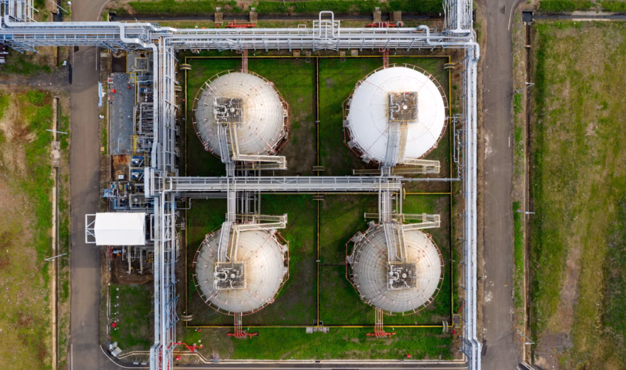Achteraanzicht van vier grote sferische opslagtanks voor butaan en propaan gas, verbonden via een uitgebreid pijpleidingsysteem op een industriële installatie.