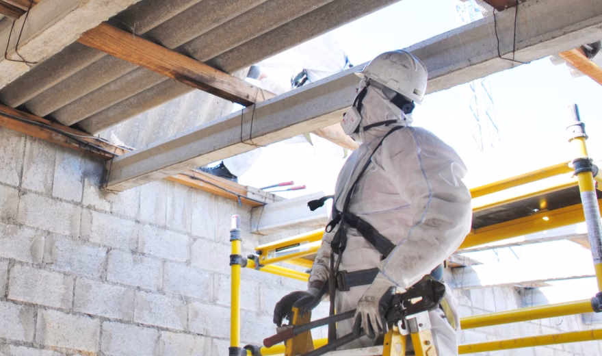 Un employé en tenue de protection effectue des travaux lors d'un inventaire de l'amiante dans un bâtiment