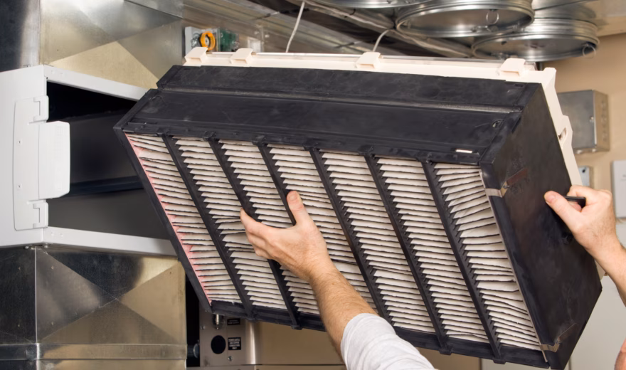 Monteur plaatst een luchtfilter in een HVAC‑unit tijdens installatie van het ventilatiesysteem.