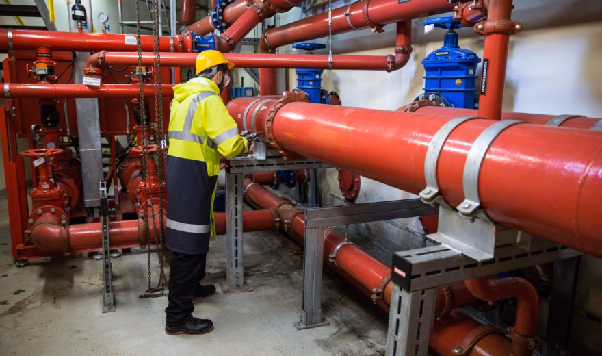 Un employé procède à l'inspection des canalisations et des composants techniques d'une installation industrielle.