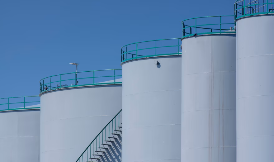 Grote opslagtanks voorzien van toegangstrappen en veiligheidsrelingen op een industriële locatie.