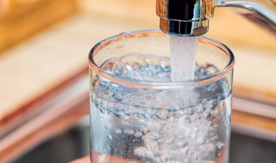 Un verre est rempli d'eau du robinet dans le cadre de la consommation d'eau potable et de la qualité de l'eau.