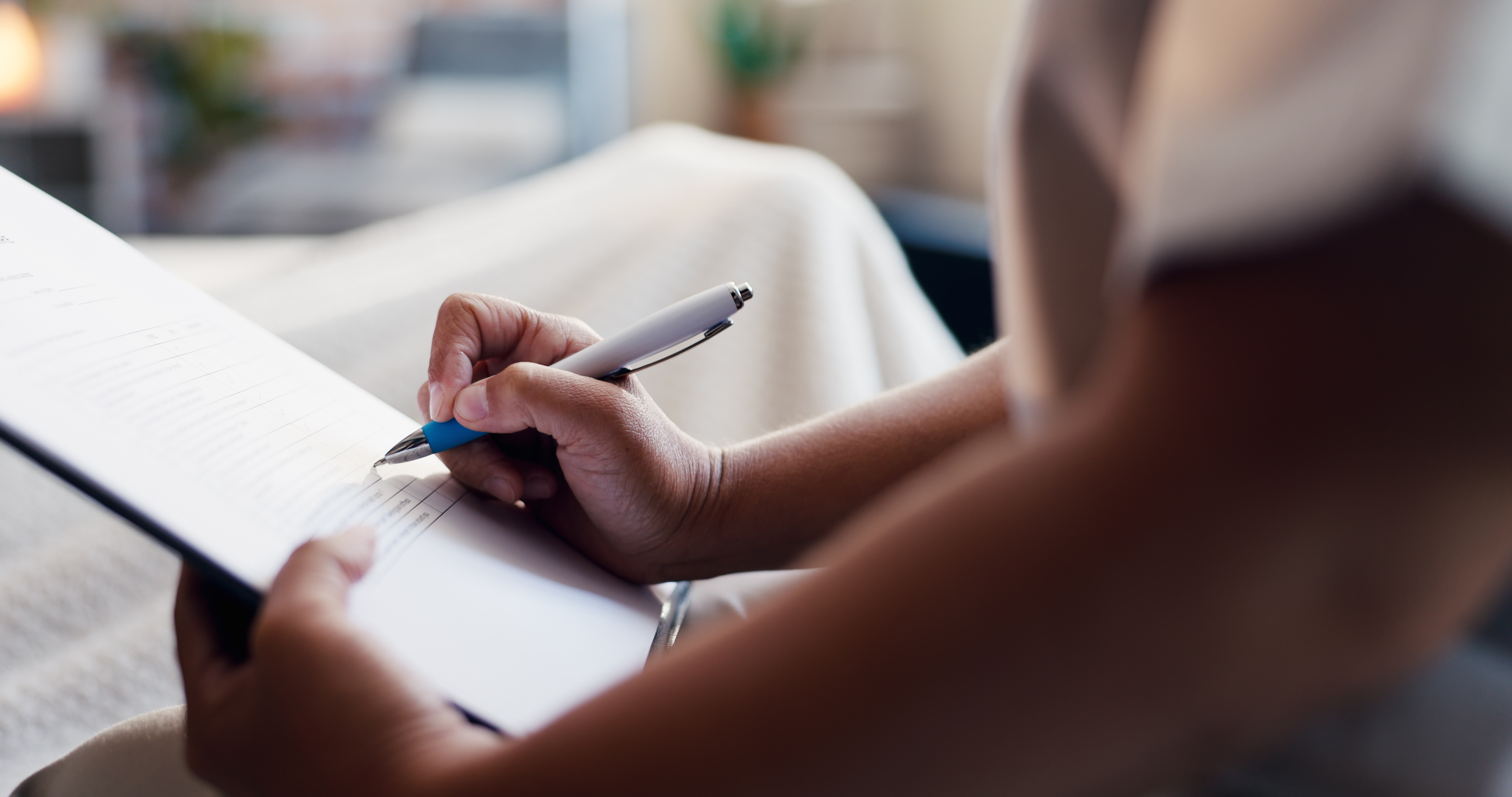 Eine Person macht während einer Inspektion, einer Bewertung oder eines Verwaltungsprozesses mit einem Stift Notizen auf einem Formular oder einer Checkliste.