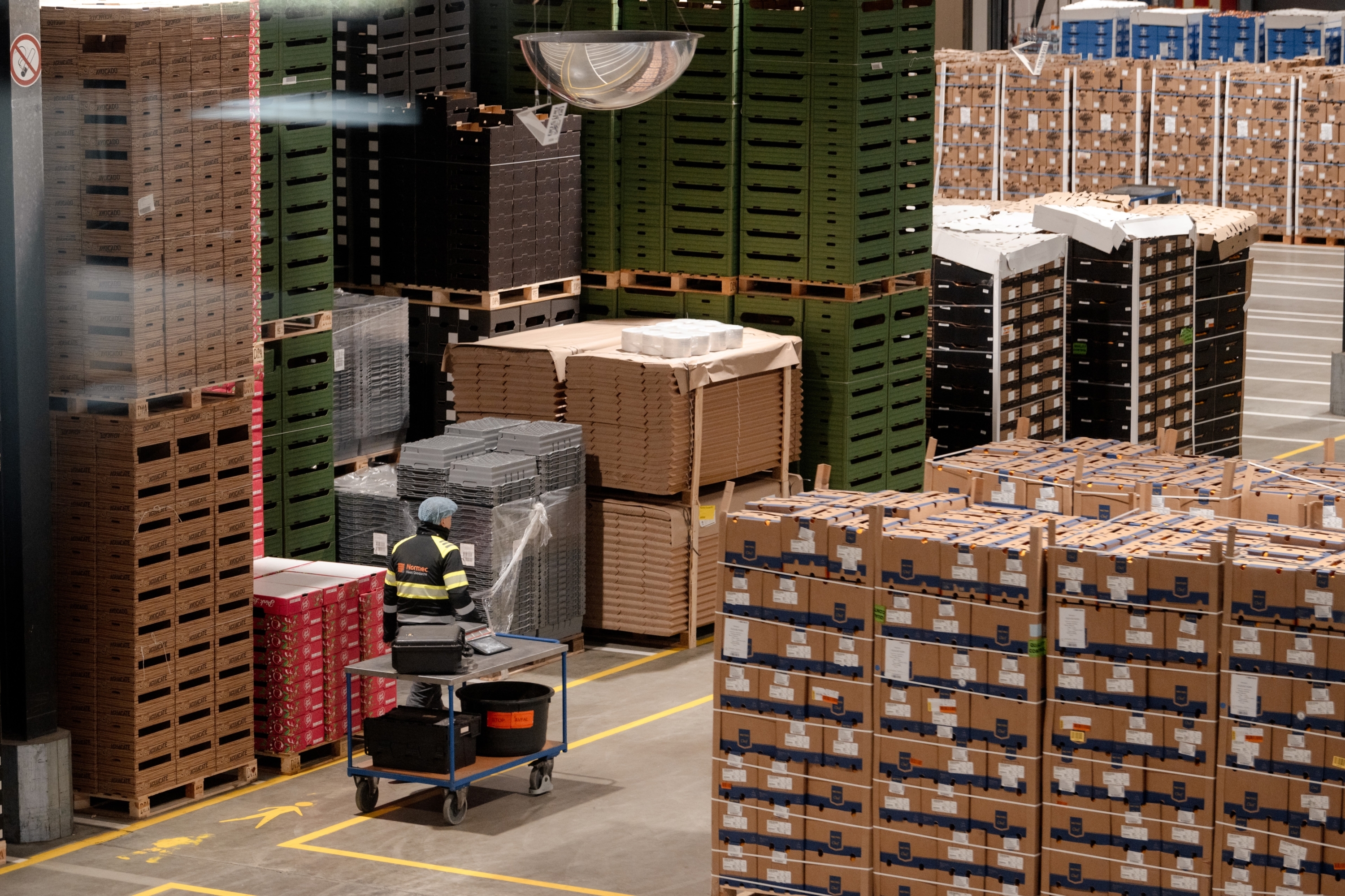 Magazijn met gestapelde pallets, kartonnen dozen en een autonome mobiele robot voor intern transport.