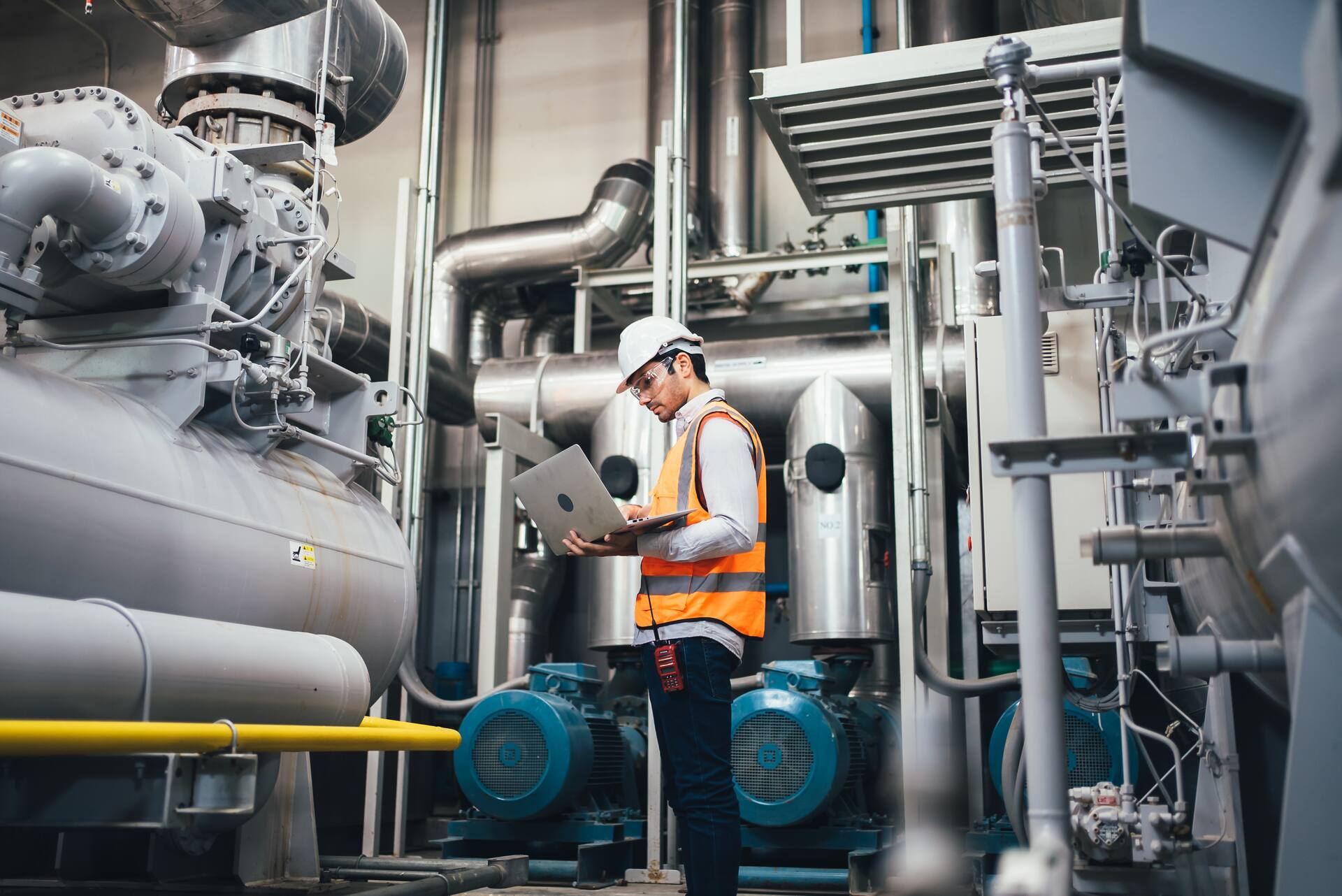 Un technicien contrôle une installation industrielle et enregistre les données d'inspection à l'aide d'un ordinateur portable.