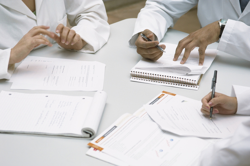 Professionals are discussing documents and taking notes during a meeting at a conference table.